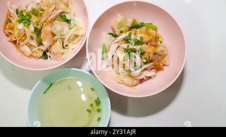 Zwei Schüsseln Garnelenwonton-Nudeln und eine Schüssel Suppe wurden auf den Tisch gestellt. Stockfoto