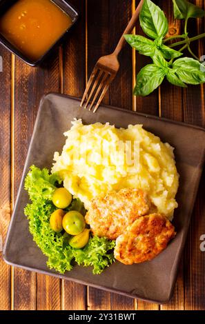 Hähnchenkoteletts mit Kartoffelpüree, Fleischkoteletts mit Kartoffelpüree und Tomaten auf einem Teller Stockfoto