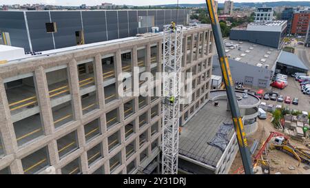 Luftaufnahme einer Baustelle mit Kränen, Baufahrzeugen und Baumaterialien. Bauarbeiter, die große Krane mit sma entfernen Stockfoto