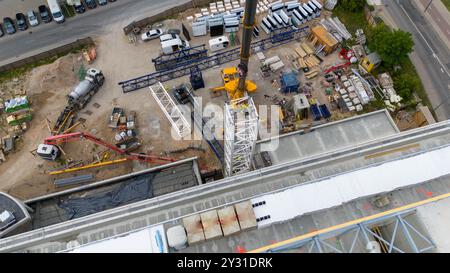 Luftaufnahme einer Baustelle mit Kränen, Baufahrzeugen und Baumaterialien. Bauarbeiter, die große Krane mit sma entfernen Stockfoto