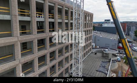 Luftaufnahme einer Baustelle mit Kränen, Baufahrzeugen und Baumaterialien. Bauarbeiter, die große Krane mit sma entfernen Stockfoto