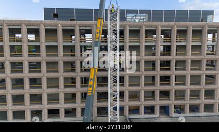 Luftaufnahme einer Baustelle mit Kränen, Baufahrzeugen und Baumaterialien. Bauarbeiter, die große Krane mit sma entfernen Stockfoto