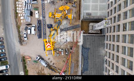 Luftaufnahme einer Baustelle mit Kränen, Baufahrzeugen und Baumaterialien. Bauarbeiter, die große Krane mit sma entfernen Stockfoto