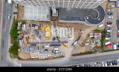 Luftaufnahme einer Baustelle mit Kränen, Baufahrzeugen und Baumaterialien. Bauarbeiter, die große Krane mit sma entfernen Stockfoto