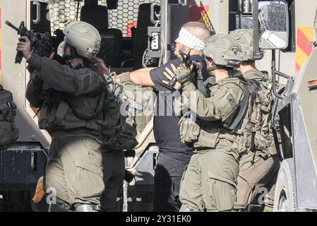 Tubas, Palästina. September 2024. Israelische Soldaten verhaften Palästinenser, nachdem sie sein Haus während des Überfalls auf Tubas überfallen hatten. Ein groß angelegter israelischer Militärangriff auf die Stadt Tubas im nördlichen besetzten Westjordanland, bei dem fünf Palästinenser bei einem Luftangriff getötet wurden und Truppen ein palästinensisches Krankenhaus umzingelten und das medizinische Personal daran hinderten, Patienten zu und von dort zu transportieren. Quelle: SOPA Images Limited/Alamy Live News Stockfoto