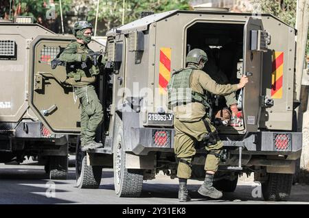 Tubas, Palästina. September 2024. Israelische Soldaten besteigen ihre Fahrzeuge, nachdem sie während des Überfalls auf Tubas ein palästinensisches Haus überfallen hatten. Ein groß angelegter israelischer Militärangriff auf die Stadt Tubas im nördlichen besetzten Westjordanland, bei dem fünf Palästinenser bei einem Luftangriff getötet wurden und Truppen ein palästinensisches Krankenhaus umzingelten und das medizinische Personal daran hinderten, Patienten zu und von dort zu transportieren. Quelle: SOPA Images Limited/Alamy Live News Stockfoto