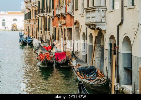 Farbenfrohe Gondeln ruhen entlang der ruhigen Kanäle von Venedig, die den Charme der Stadt widerspiegeln. Gebäude mit klassischer Architektur säumen den Wasserweg und schaffen eine malerische Atmosphäre. Stockfoto