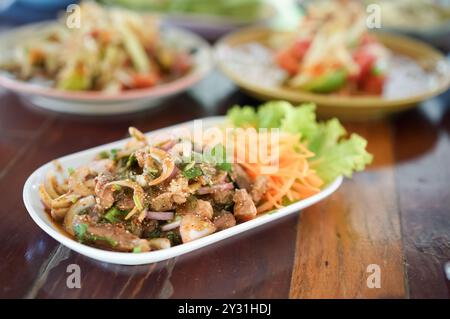 Thailändischer gegrillter Schweinehals mit würziger Dip-Sauce. Würziger gegrillter Schweinekalat mit frischem Gemüse auf Holztisch, fertig zum Verzehr. Stockfoto