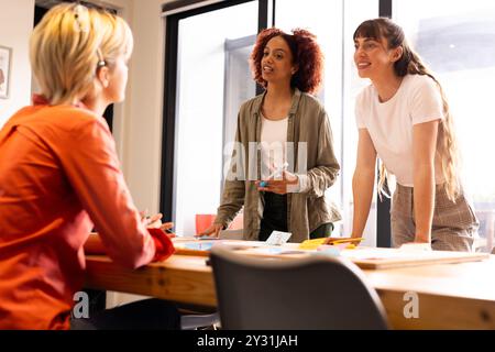 Zusammenarbeit bei kreativem Schreibprojekt, drei multirassische Frauen diskutieren Ideen im Büro Stockfoto