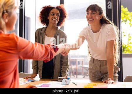 Im Büro, Händeschütteln, multirassische Frauen in Geschäftsbesprechungen über kreative Ideen zum Schreiben Stockfoto