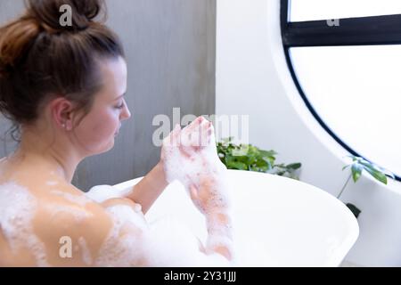 Zu Hause, entspannend in der Badewanne, junge Frau genießt Sprudelbad in Spa-Umgebung Stockfoto