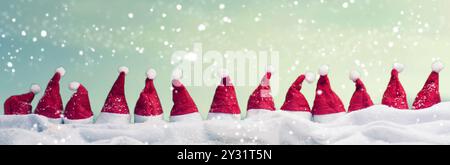 Viele Hüte von Santa in einer Reihe mit Schnee, Weihnachten Hintergrund, Panoramaaussicht Stockfoto