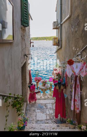 Rovinj Kroatien 27. August 2024, im Herzen von Rovinj hängen bunte Kleidungsstücke entlang einer engen Gasse, die zu einem malerischen Tisch am Wasser führen Stockfoto