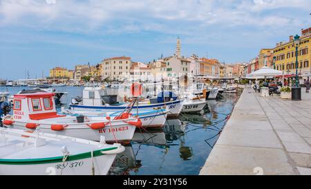 Rovinj Kroatien 27 August 2024 lebhafte Fischerboote schweben sanft im ruhigen Wasser des Hafens von Rovinj und spiegeln malerische Pastellgebäude unter einem Klo wider Stockfoto