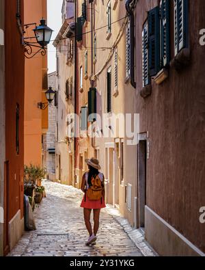 Ein Reisender schlendert durch eine malerische Gasse in Rovinj, Kroatien, umgeben von bunten Gebäuden und Laternen. Die Sonne taucht die pulsierende Szene, kreat Stockfoto