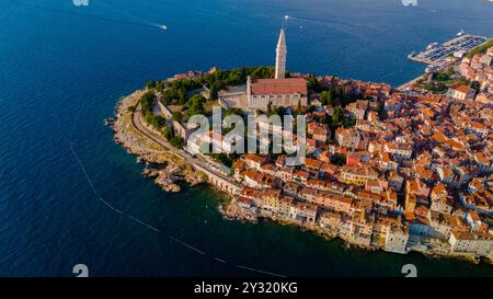 Ein atemberaubender Blick auf Rovinj entlang der Adriaküste zeigt farbenfrohe Gebäude an einem felsigen Ufer, die ihre reiche Geschichte, wunderschöne Architektur und einladendes Wasser unter klarem Himmel zeigen. Stockfoto