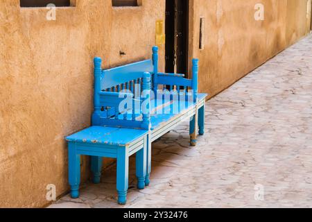 Alte traditionelle blau lackierte Holzbank mit kleinem Tisch in der Straße oder im Innenhof. Holzsofa im Freien im arabischen Stil im Haus. Stockfoto