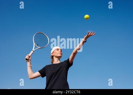 Mädchen-Tennisspielerin macht einen Hit mit einem Tennisschläger auf einem Ball Nahaufnahme auf einem Himmelsgrund, Konzept eines Tennisspiels Stockfoto