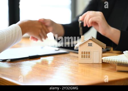 Immobilienmakler schüttelt mit ein paar Kunden nach Vertragsunterzeichnung. Kaufkonzept für Immobilien Stockfoto