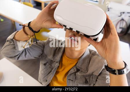 Mit dem VR-Headset erkundet der asiatische Teenager die virtuelle Realität im Klassenzimmer Stockfoto