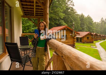 Morgenkaffee und Entspannung mit einem digitalen Gerät auf einem gemütlichen Holzbalkon in der Natur Stockfoto