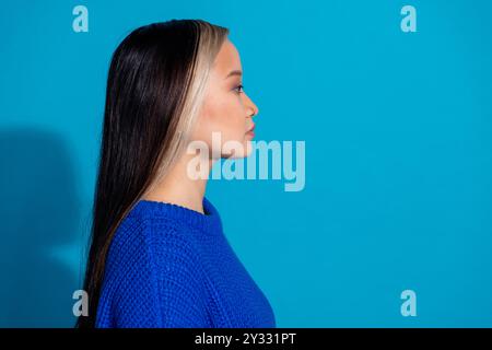 Foto-Porträt der schönen jungen Dame Profil Blick leer Raum gekleidet stilvolle Strickkleidung Kleid isoliert auf blauem Hintergrund Stockfoto