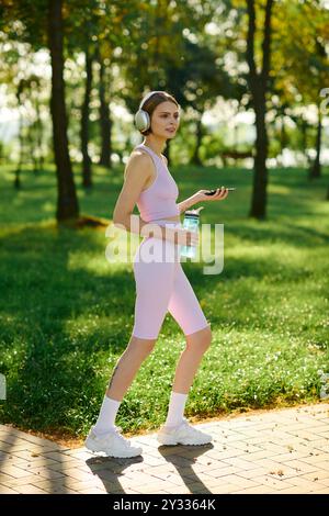 Eine Frau läuft durch den Park, trägt Kopfhörer und genießt die frische Luft. Stockfoto