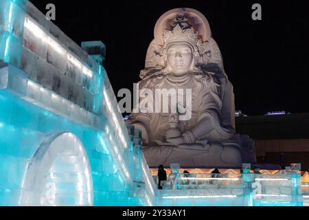 1. Januar 2022, HARBIN, CHINA. Vertikales Bild spektakulärer beleuchteter weißer Eisskulpturen in Harbin, China. Nachtbild mit Kopierraum für Tex Stockfoto