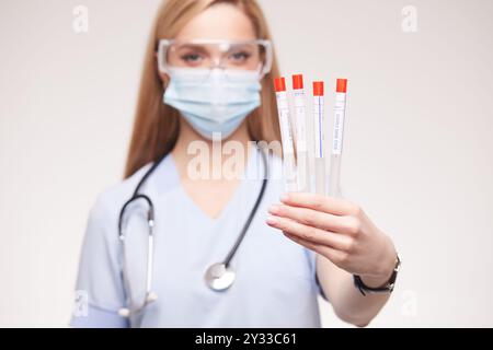 Arzt hält sterilen Tupfer Stick nah oben auf weißem Hintergrund, Analyse der medizinischen Testergebnisse, Gesichtsmaske für Sicherheit in der Klinik, medizinische Tests Stockfoto