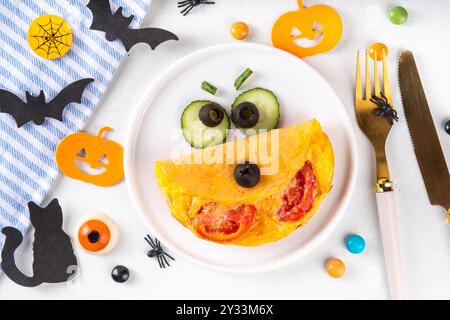 Halloween Frühstückseier Omelett geformt und dekoriert wie ein süßes Monster, mit frischem Gemüse, lustigen Kindern Halloween Essen einfache Rezeptidee Stockfoto
