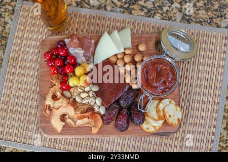 Eine köstliche Wurstplatte mit verschiedenen Käsesorten, Früchten, Nüssen und Aufstrichen auf einem Holzbrett ist ein gesunder und schneller Snack. Stockfoto