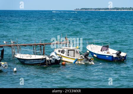 Porec, Istrien, Kroatien - 27. August 2024: Kleine Fischerboote schwimmen neben einem alten Holzsteg auf dem Meer vor der Küste von Porec *** kleine Fischerboote schwimmen neben einem alten Holzsteg auf dem Meer vor der Küste von Porec Stockfoto