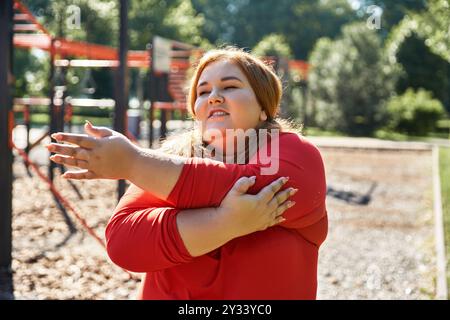 Eine Frau in Übergröße genießt ihre Fitness-Routine, während sie sich im Freien dehnt. Stockfoto