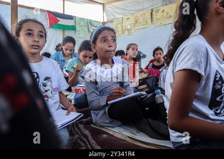 Gaza, Gaza, Palästina. September 2024. Die palästinensische Lehrerin Israa Abu Mustafa ergriff die Initiative, ein Klassenzimmer mit 30 Schülern in einem Zelt auf den Ruinen ihres zerstörten Hauses einzurichten, um Kinder zu unterrichten, wenn das neue Schuljahr beginnt und die Schüler aufgrund des Krieges nicht regelmäßig zur Schule gehen. Im Lager Khan Younis im südlichen Gazastreifen, 12. September 2024. Das palästinensische Bildungsministerium gab zu Beginn des Studienjahres 2024/2025 eine Erklärung ab, in der es heißt, dass Studenten im Gazastreifen ihr Recht auf Bildung entzogen werden. Mehr als 650.000 männlich und f Stockfoto