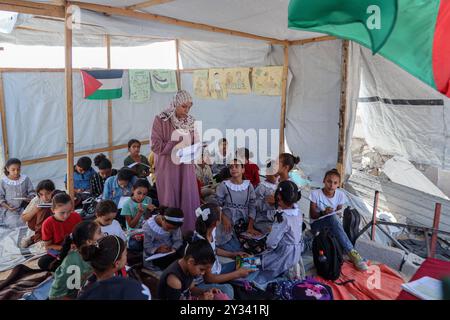 Gaza, Gaza, Palästina. September 2024. Die palästinensische Lehrerin Israa Abu Mustafa ergriff die Initiative, ein Klassenzimmer mit 30 Schülern in einem Zelt auf den Ruinen ihres zerstörten Hauses einzurichten, um Kinder zu unterrichten, wenn das neue Schuljahr beginnt und die Schüler aufgrund des Krieges nicht regelmäßig zur Schule gehen. Im Lager Khan Younis im südlichen Gazastreifen, 12. September 2024. Das palästinensische Bildungsministerium gab zu Beginn des Studienjahres 2024/2025 eine Erklärung ab, in der es heißt, dass Studenten im Gazastreifen ihr Recht auf Bildung entzogen werden. Mehr als 650.000 männlich und f Stockfoto