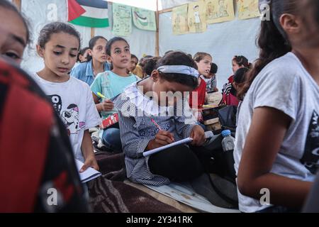 Gaza, Gaza, Palästina. September 2024. Die palästinensische Lehrerin Israa Abu Mustafa ergriff die Initiative, ein Klassenzimmer mit 30 Schülern in einem Zelt auf den Ruinen ihres zerstörten Hauses einzurichten, um Kinder zu unterrichten, wenn das neue Schuljahr beginnt und die Schüler aufgrund des Krieges nicht regelmäßig zur Schule gehen. Im Lager Khan Younis im südlichen Gazastreifen, 12. September 2024. Das palästinensische Bildungsministerium gab zu Beginn des Studienjahres 2024/2025 eine Erklärung ab, in der es heißt, dass Studenten im Gazastreifen ihr Recht auf Bildung entzogen werden. Mehr als 650.000 männlich und f Stockfoto