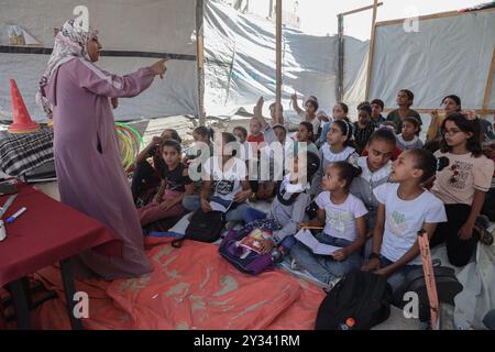 Gaza, Gaza, Palästina. September 2024. Die palästinensische Lehrerin Israa Abu Mustafa ergriff die Initiative, ein Klassenzimmer mit 30 Schülern in einem Zelt auf den Ruinen ihres zerstörten Hauses einzurichten, um Kinder zu unterrichten, wenn das neue Schuljahr beginnt und die Schüler aufgrund des Krieges nicht regelmäßig zur Schule gehen. Im Lager Khan Younis im südlichen Gazastreifen, 12. September 2024. Das palästinensische Bildungsministerium gab zu Beginn des Studienjahres 2024/2025 eine Erklärung ab, in der es heißt, dass Studenten im Gazastreifen ihr Recht auf Bildung entzogen werden. Mehr als 650.000 männlich und f Stockfoto