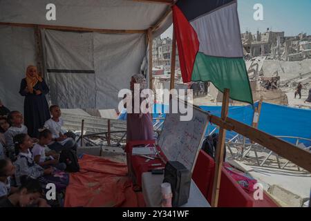 Gaza, Gaza, Palästina. September 2024. Die palästinensische Lehrerin Israa Abu Mustafa ergriff die Initiative, ein Klassenzimmer mit 30 Schülern in einem Zelt auf den Ruinen ihres zerstörten Hauses einzurichten, um Kinder zu unterrichten, wenn das neue Schuljahr beginnt und die Schüler aufgrund des Krieges nicht regelmäßig zur Schule gehen. Im Lager Khan Younis im südlichen Gazastreifen, 12. September 2024. Das palästinensische Bildungsministerium gab zu Beginn des Studienjahres 2024/2025 eine Erklärung ab, in der es heißt, dass Studenten im Gazastreifen ihr Recht auf Bildung entzogen werden. Mehr als 650.000 männlich und f Stockfoto