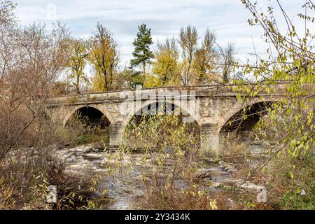 Alte Steinbrücke über den Fluss. Herbstperspektive, Details aus den Straßen von Debnevo, Dorf in Nordbulgarien Stockfoto