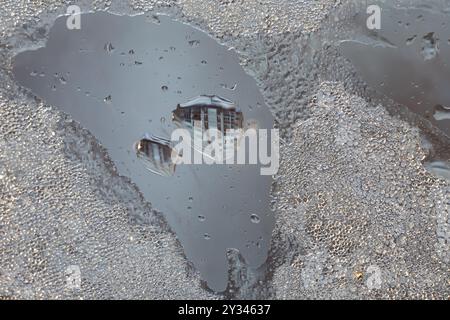 Eisauftauende Fensterscheiben und Wassertropfen spiegeln das Haus gegenüber wider. Urbaner Winterhintergrund, selektiver Fokus. Ultra-Makrofotografie. Stockfoto