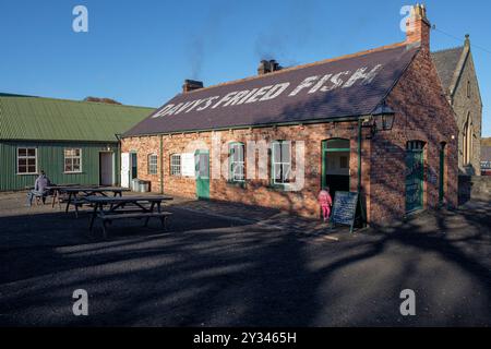 Ein junges Mädchen in einem farbenfrohen Jackenmantel betritt Davy's Fish and Chip Shop, Beamish Open-Air Museum, Stanley, County Durham, England, Großbritannien, Stockfoto