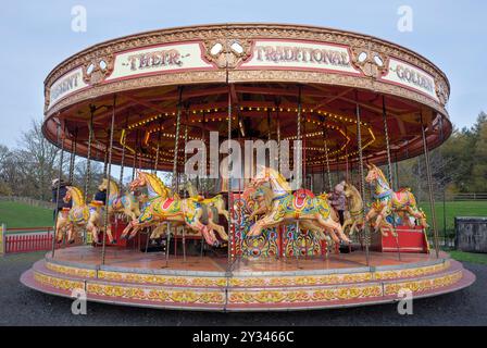 Eine Fahrt auf dem Karussell mit einem kleinen Kind und ein paar Erwachsenen, die auf den Pferden reiten, im Freilichtmuseum Beamish, County Durham, England, Großbritannien. Stockfoto