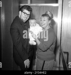 Aktenfoto vom 11/1964 von Rolf Harris mit seiner Frau Alwen und der sieben Monate alten Tochter Bindi am Flughafen London. Harris' Frau Alwen Hughes starb im Alter von 92 Jahren knapp ein Jahr nachdem der in Ungnade gefallene Entertainer zu Hause in Bray, Berkshire, starb. Die walisische Bildhauerin und Juwelierin heiratete 1958 Harris und blieb bei ihrem Mann, nachdem er wegen unanständigen Übergriffs auf junge Mädchen verurteilt wurde. Ausgabedatum: Donnerstag, 12. September 2024. Stockfoto