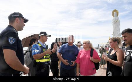 (240912) -- SANYA, 12. September 2024 (Xinhua) -- Ein serbischer Polizeibeamter spricht mit Touristen, während er in der Nanshan Kulturtourismuszone in Sanya, südchinesischer Provinz Hainan, am 12. September 2024 patrouilliert. Auf Einladung des chinesischen Ministeriums für öffentliche Sicherheit kamen sechs Polizeibeamte aus Serbien zu einer einmonatigen gemeinsamen Polizeipatrouillenmission nach China. Während dieser Zeit wird die serbische und chinesische Polizei die Touristenattraktionen in Hainan und der ostchinesischen Provinz Zhejiang patrouillieren. Nach der Vereinbarung zwischen den beiden Seiten wird die serbische Polizei mit ihrem Chin zusammenarbeiten Stockfoto