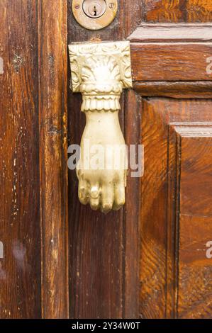 Weiße Tür Klopfer wie eine Hand auf einer Eiche Tür geformt Stockfoto