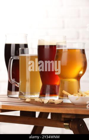 Gläser mit verschiedenen Biersorten und Snacks auf Holztisch Stockfoto