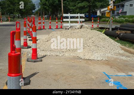 Verkehrskegel, ein Schotterhaufen und Rohrabschnitte markieren den Beginn eines Wasserhauptaustauschprojekts. Stockfoto