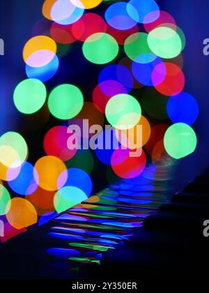 Verschwommene Bokeh-Weihnachtslichter, die sich in Klaviertasten spiegeln. Konzept für Weihnachten und Neujahrsfeier. Hintergrundbild, Banner. Stockfoto