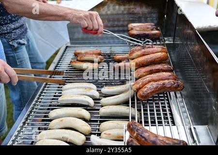 Großer Grill mit Würstchen zum Verkauf auf einem Open-Air-Festival, in Deutschland Bratwurst genannt und ist ein typisches Outdoor-Fast Food, ausgewählter Fokus, schmaler Dep Stockfoto