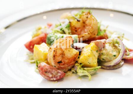 Salat aus gebratenen Garnelen, Mango, Avocado und Tomaten mit Kräuterdressing auf einem weißen Teller, Partygericht oder frischer Meeresfrüchtevorspeise in einem Menü, Kopierraum, Sell Stockfoto